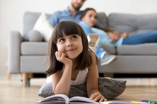 Daughter dreaming lying on warm floor with book at home