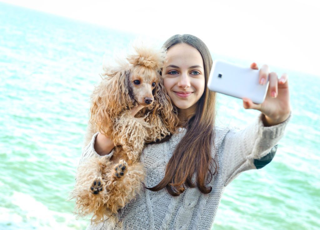 Girl taking selfies of herself and dog.